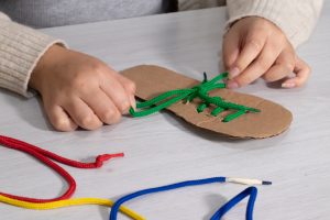 Ребенок пытается завязать шнурки
