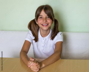 Девочка улыбается за партой